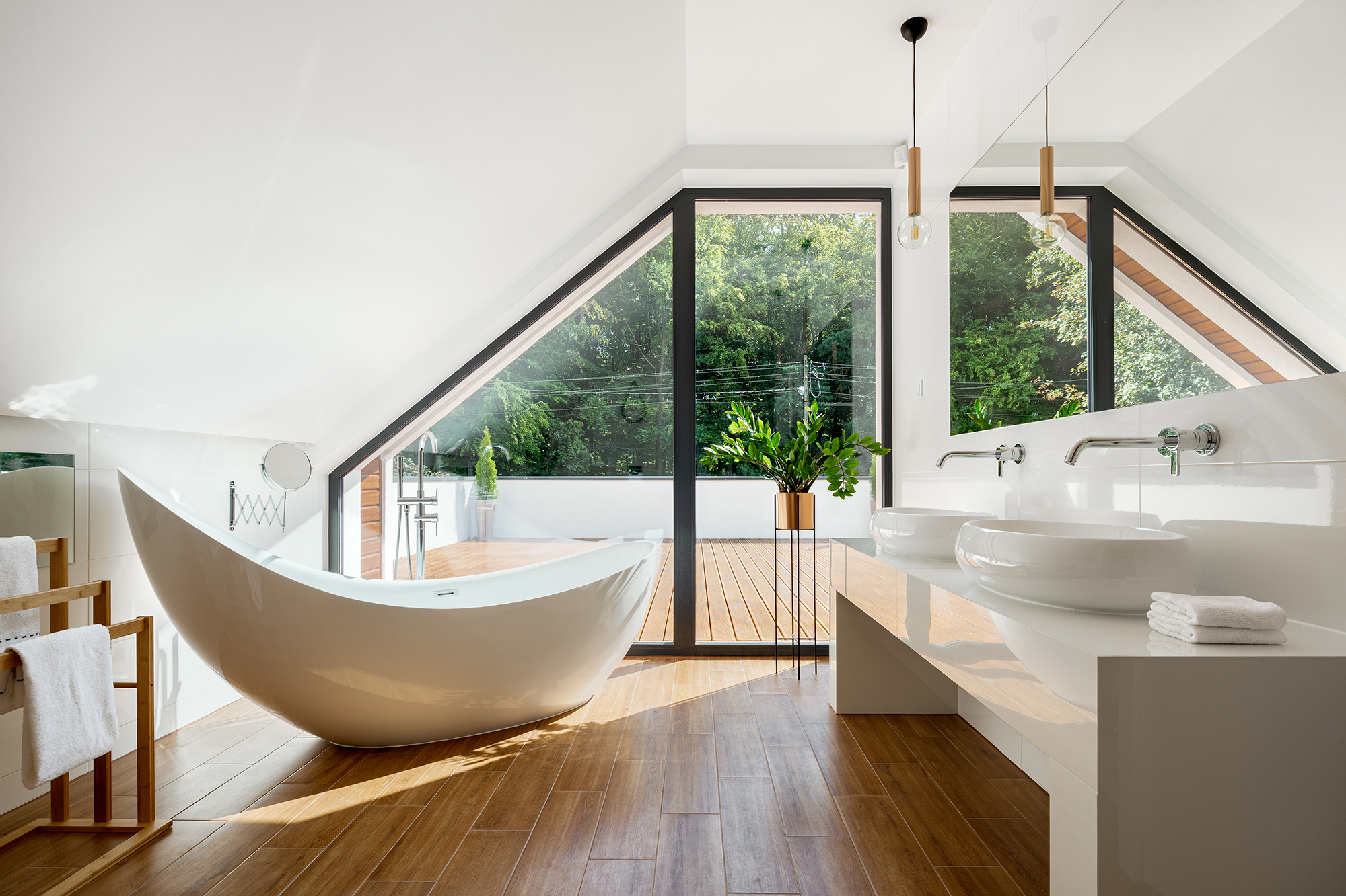 Elegant attic bathroom with stylish bathtub, wooden floor and balcony door