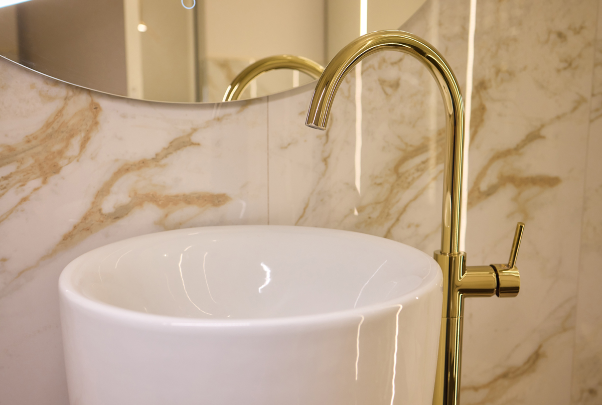 A gold faucet adorns a sleek rectangular sink in a bathroom, The elegant plumbing fixture enhances the overall aesthetic of the space